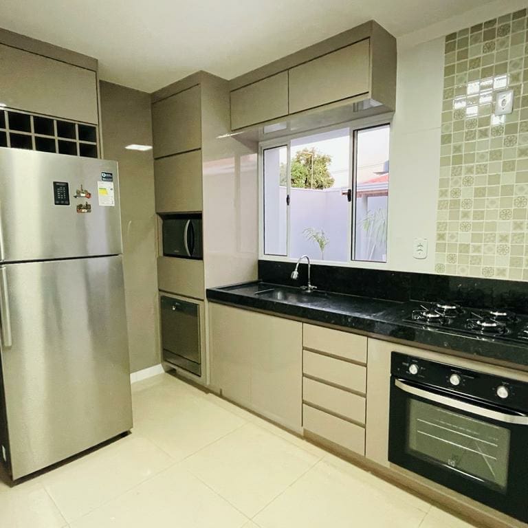 Quarto com a cama e três travesseiros, mesa de
                          cabeceiro branca, com abajur e vasos