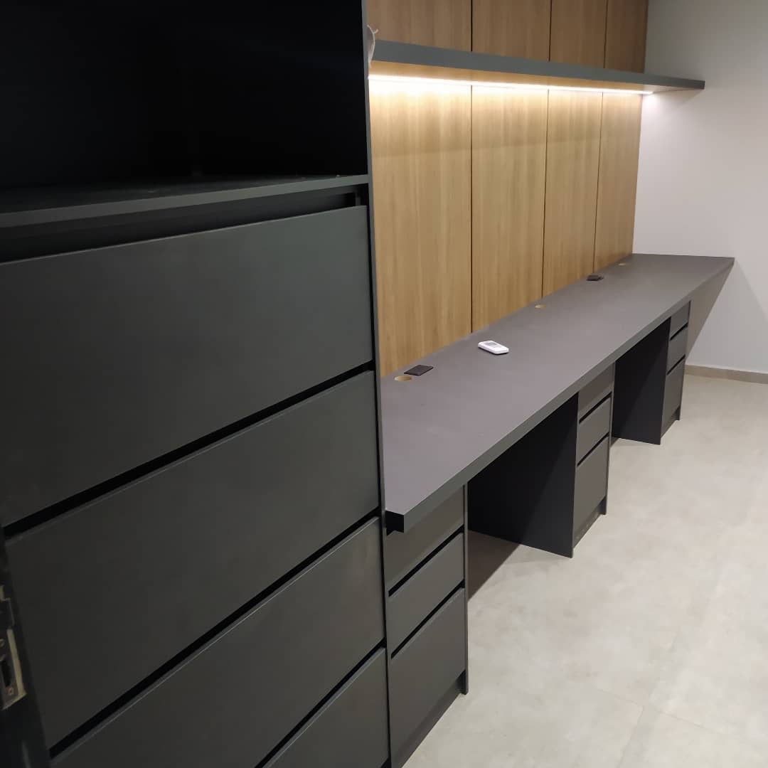 Imagem de uma copa com bancada de madeira, taças,
                          talheres, geladeira de inox e armário em cinza